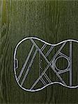 A line drawing image on a natural wood grain background.  The sound board and body of a musical instrument, a guitar.