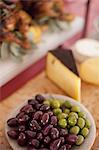 A buffet table laid out for a party. Organic food. A cheese board selection, and a plate of green and black olives.