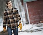 An organic farm in winter in New York State, USA. A man in a plaid shirt walking across snowcovered ground.