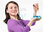 A young girl holding a conical flask of blue liquid in front of an evaporation cycle illustration on a clear surface.