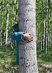 Ten year old girl standing behind commercially grown poplar tree on large tree farm, near Pendleton