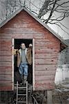 An organic farm in upstate New York, in winter. A man standing in the doorway of a henhouse.