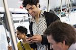 New York City park. People, men and women on a city bus. Public transport. Keeping in touch. A young man checking his cell phone.