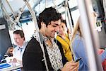 New York City park. People, men and women on a city bus. Public transport. Keeping in touch. A young man checking his cell phone.