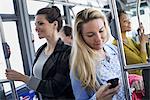 New York City park. People, men and women on a city bus. Public transport. Keeping in touch. A young woman checking or using her cell phone.