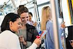 New York City park. People, men and women on a city bus. Public transport. Two women looking at a handheld digital tablet.