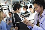 New York City park. People, men and women on a city bus. Public transport. Keeping in touch. A young woman checking or using her cell phone.