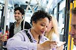 New York City park. People, men and women on a city bus. Public transport. Keeping in touch. A young woman checking or using her cell phone.