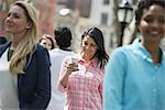 People outdoors in the city in spring time. New York City park. Three women, one checking her mobile phon.