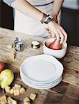 A woman in a domestic kitchen cooking. Dipping fresh organic pears into a sauce for dessert. Fresh ingredients. Brown sugar cubes.