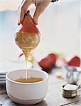 A woman in a domestic kitchen cooking. Dipping fresh organic pears into a sauce for dessert. Fresh ingredients. Brown sugar cubes