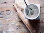 A domestic kitchen. A small group of objects. A rolling pin and jar of flour on a worn tabletop. View from above.