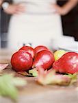 A domestic kitchen tabletop. A small group of fresh organic pears and a stack of white plates.