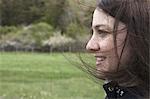 A young woman in profile. Her brown hair blowing about her face. Outdoors. Spring.