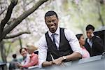 City life in spring. Young people outdoors in a city park. A man sitting down, with four people in the group behind him.