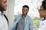 Outdoors in the city in spring. An urban lifestyle. A man looking at the camera, with two people in the foreground.