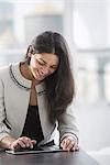 Young professionals at work. A woman at a work table using a digital tablet.