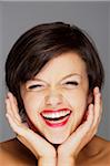 Head and Shoulders Portrait of Mid-Adult Woman Laughing with Grey Background