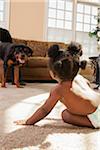 Baby Girl Playing on Carpet looking at Pet Rottweiler