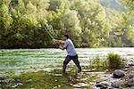 mid adult man on holidays on river, relaxing and fishing trout