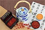 Safflower tea with oriental style teapot and spoon and chinese calligraphy over bamboo. Hong hua.