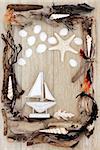 Sea shell, driftwood and seaweed abstract design with small boat over old oak background.