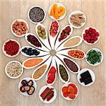 Healthy super food selection in white porcelain bowls over oak wood background