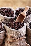 Roasted coffee in bags with wooden scoop on golden background