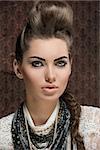 close-up shoot of fashion creative brunette girl posing with elegant hair-style and strong make-up,  white lace shirt and a lot of necklaces