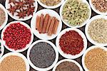 Spice and herb selection in china bowls over bamboo background.