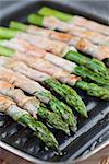 Prosciutto wrapped green asparagus on a grilling pan