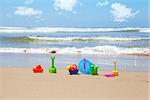 Plastic beach toys on beach with sea and clouds in background