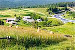 Summer mountain village outskirts with haystacks on field and road (Carpathian, Ukraine)