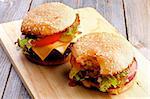 Twoe Hamburgers with Beef, Tomato, Lettuce, Pickle, Red Onion and Cheese on Sesame Buns