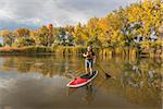 senior male paddler enjoying workout on stand up paddleboard (SUP), calm lake in Colorado, fall colors