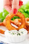 Woman's hand holding delicious fried onion rings