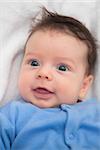 Studio portrait of a happy 2 months old baby boy with blue top.