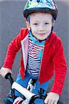 cute cheerful little boy in helmet riding bicycle