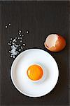 Fresh raw egg and sea salt on a black board.