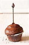 Delicious chocolate muffin cupcake with silver spoon on a rustic wooden board close-up.