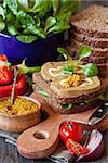 Tasty pate sandwich with mustard sause, vegetables and bowl of fresh baby bok choy on a wooden background.