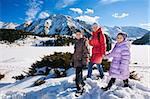 Family (mother with two children) take a walk on winter mountain slope (Big Almaty Lake, Kazakhstan)