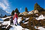 Family (mother with two children) take a walk on winter mountain slope (Big Almaty Lake, Kazakhstan)