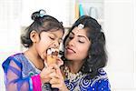 Eating ice-cream. Happy Asian India family sharing ice-cream at home. Beautiful Indian child licking ice-cream cone.