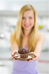 Closeup on young woman showing chocolate muffin