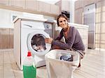 Close up of a young woman putting a cloth into washing machine