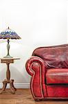 Luxurious Red Leather Couch and Lamp Details in front of a blank wall to ad your text, logo, images, etc.