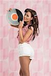 portrait of sexy american pin-up with white shorts posing and taking vinyl disc