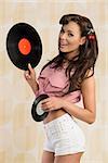 fashion portrait of sexy brunette girl with vintage pin-up style smiling and taking vinyl LP in the hand