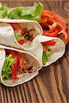 burrito with meat and ingredients on old wooden table rustic style